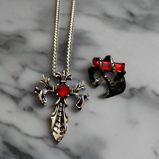 A set consisting of a pendant necklace and a ring, with both featuring a gothic design with red gemstones and black elements on a black background.