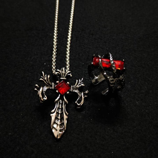 Silver cross necklace with red gemstones on a black background
